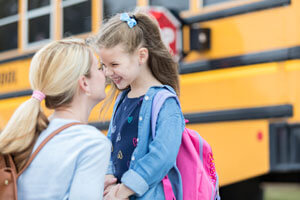 Mom saying bye to daughter at school bus