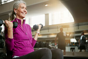 older woman lifting dumbbells at gym