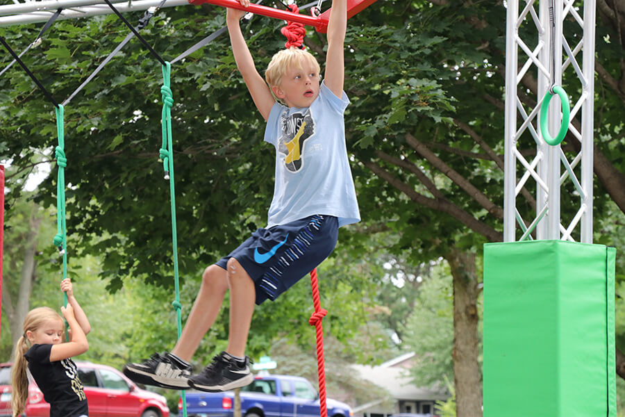 young blond child handing from the playground monkey bars